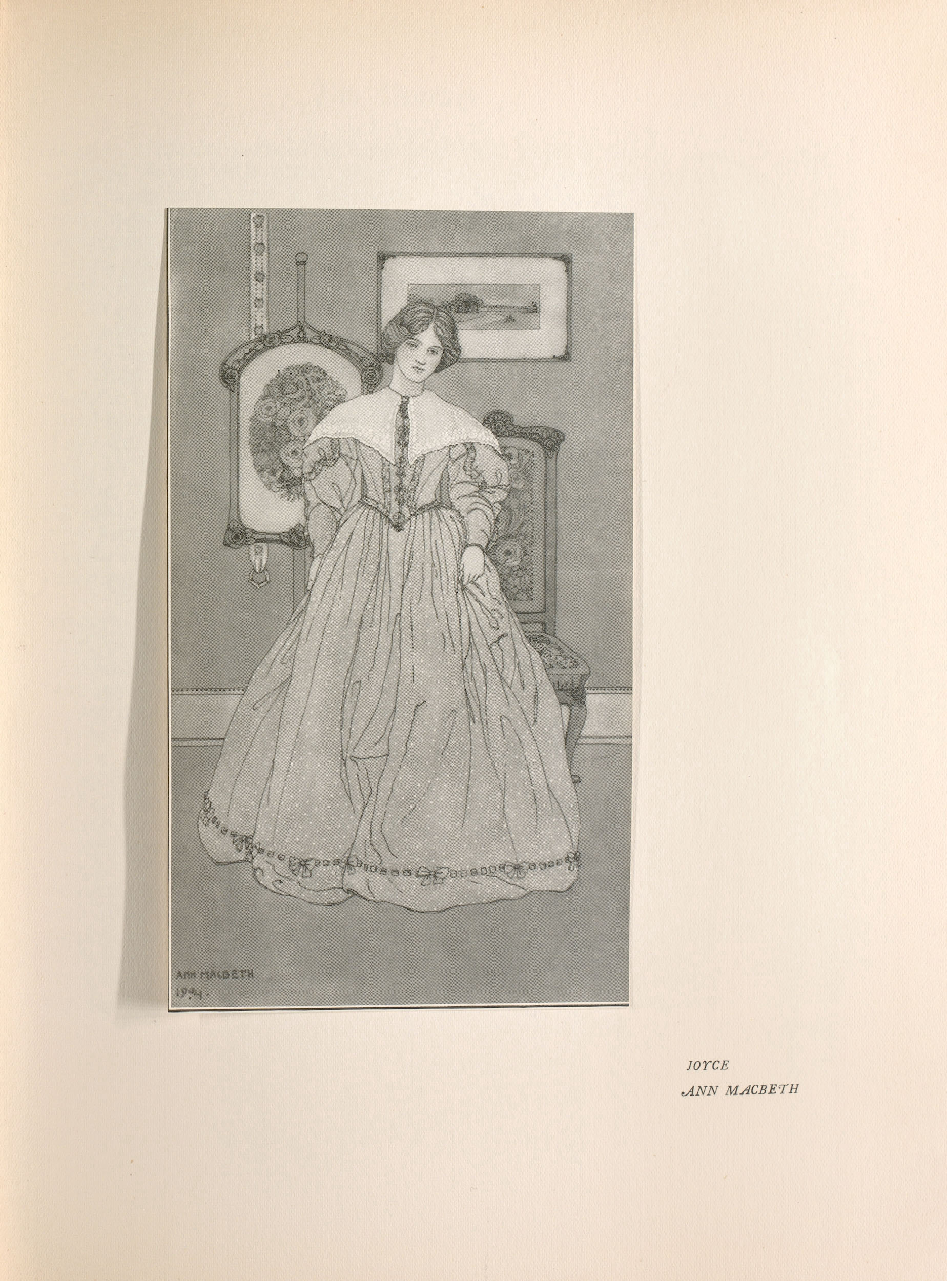 The tonal image is in portrait orientation and is centered on the page. A young woman in the foreground stands upright in an aesthetic drawing room, facing forward. She is wearing a full-length dotted gown with wide sleeves and a cinched waistline; the bottom edge of the gown is threaded with a ribbon and bows.. Her shoulders are covered with a white shawl. Behind the woman, there is a wooden chair upholstered in a floral textile. Two works of art are hung on the wall behind her: a small framed landscape painting and a framed piece of floral embroidery. The artist’s signature, “Ann Macbeth”, and the date, “1904,” are inscribed in the bottom left corner of the image.