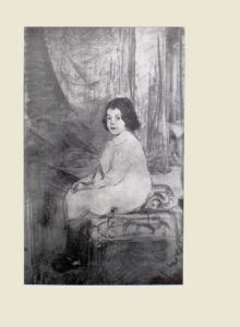 Image is of a girl sitting on a patterned ottoman with a pillow She is shown in 3 4 face with eyes looking straight ahead Her body is pointing to the left with her knees pressed together and her hands clasped in her lap She is wearing a collared long white dress that reaches her knees with dark coloured socks and shoes The girl has short, dark curly hair The background is light coloured with curtains The image is vertically displayed